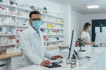 Zelfklevend Fotobehang Pharmacist with protective mask on his face while working at a pharmacy © Zamrznuti tonovi