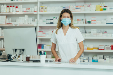 Obraz premium Pharmacist with protective mask on her face while working at a pharmacy