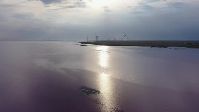 Sunset over a pink lake. Lake Lemuria (Pink Lake) is a lake in the Kherson region of Ukraine. There are wind generators on the shore. Aerial view