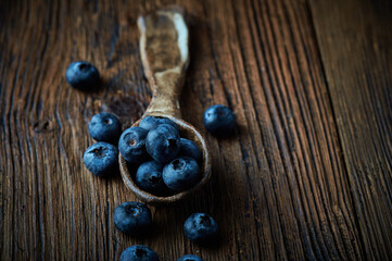 Blueberries in dark setting on wooden backround. Blueberries fruit background.Fresh blueberry in ceramic spoon.