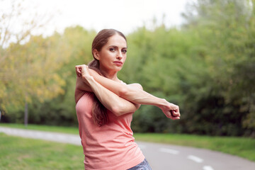 Woman runner stretching arms before running summer park