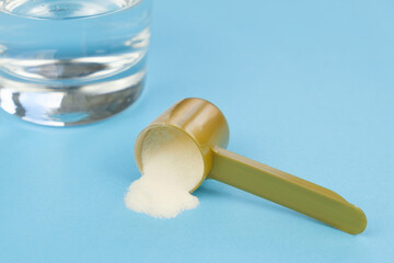 Hydrolyzed Marine Collagen Powder in measuring spoon, glass of water on a blue background. Collagen...