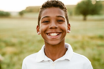 Black boy wearing white shirt smiling and looking at camera