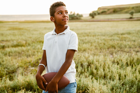 Black boy wearing white shirt posing with rugby ball - Powered by Adobe