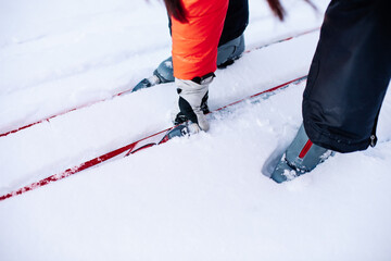 Man is skiing. Close-up of legs in gray ski boots on skis, man bent down and picked up ski lying on snow. 