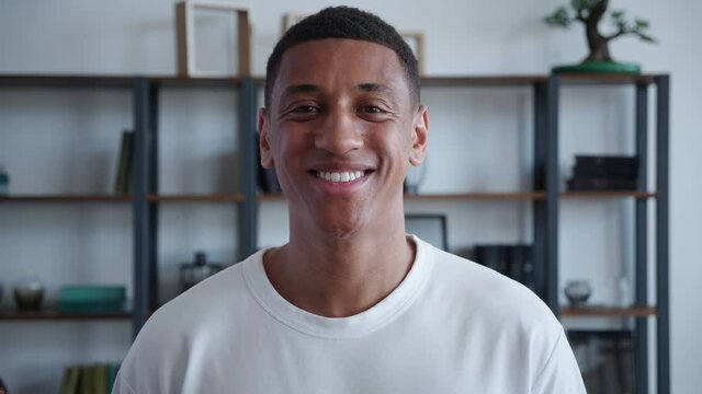Portrait of handsome man smiling while posing to camera at modern office background. Close-up of african american male looking into the camera with toothy smile