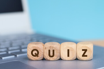 Wooden cube with QUIZ text on laptop keyboard background