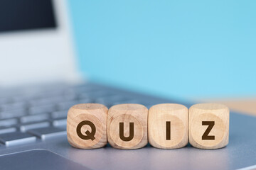 Wooden cube with QUIZ text on laptop keyboard background