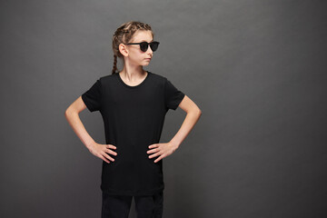 Kid girl wearing black t-shirt with space for your logo or design in studio over gray background...
