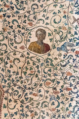 Detail of colorful ancient mosaic showing the portrait of a young man inside a circle surrounded by flowers
