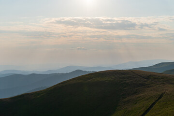 Picturesque sunset. A calm evening fell on mountain ranges overgrown with green forest. The sky is painted with the warm colors of the setting sun. Nature Ukraine, Carpathian Mountains