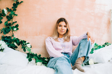 Portrait of attractive caucasian woman sitting on a bed at home in cozy bright bedroom, with...