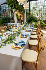 Banquet wedding table setting with blue napkins, gold cutlery, crystal, fresh flowers and candles. Wedding decorations. Soft selective focus.