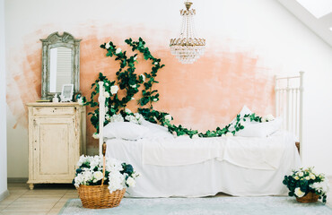 Interior of bright white bedroom with decorative flowers on a wall.