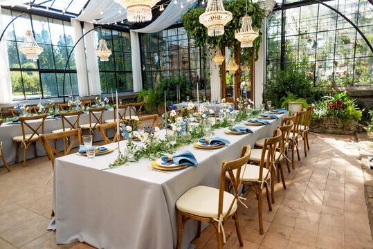 Banquet wedding table setting with blue napkins, gold cutlery, crystal, fresh flowers and candles. Wedding decorations. Soft selective focus.