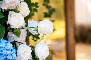 Elements of wedding decor, decorated with fresh white roses, blue orchids and candles. Wedding arch. Soft selective focus.