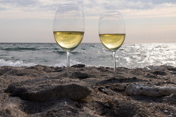 Romantic glass of white wine, on the sea beach. Wine tasting and relaxation at the resort