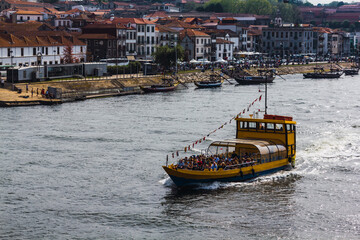 Fototapeta premium Tourist boat sailing through the river with the city in the background