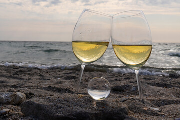 Romantic glass of white wine, on the sea beach. Wine tasting and relaxation at the resort