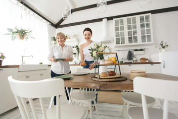 Adult daughter and her elderly mother are served in the kitchen before dinner