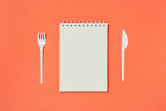 Top view of blank spiral notebook, fork and knife