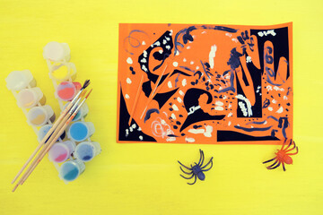 Child making card for the holiday of halloween. Funny crafts from pieces paper. Halloween decor....