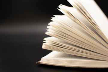 an open old book on a black background. The concept of education and development