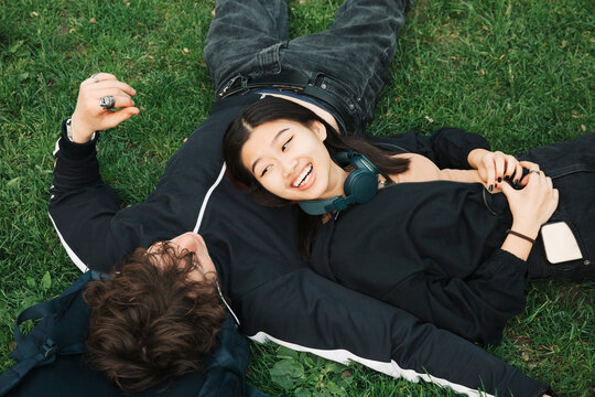 High angle view of male and female friends lying on grass at park