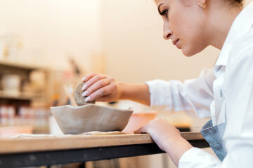 Clay and porcelain dishes to order. Ceramist woman in the workshop of individual products for the home. Master in the ceramics studio. . Uniform for convenient and comfortable work.