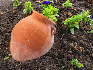 Landscape Decorative Garden Decoration. A clay jug on a flower bed as a decoration. Imitation of an...