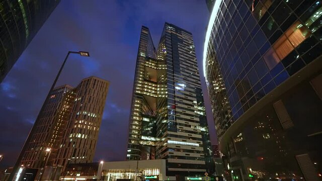 A huge business center of several high-rise towers at night. Dolly camera shot