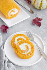 Pumpkin cake roll with cream cheese filling on a gray concrete background. Dessert for Thanksgiving or Halloween. Selective focus, copy space.