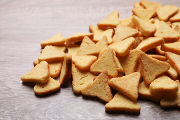 Heap of crispy rusks on wooden table, closeup