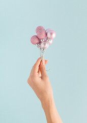 A woman's hand holds New Year's balls like flying balloons. Christmas concept.