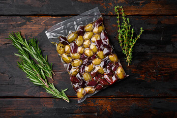 Green and black olives in pack, on old dark  wooden table background, top view flat lay, with copy...