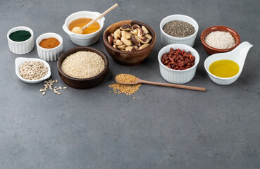 Assorted superfoods in spoons over stone background with copy space. Chia, quinoa, oat, linseed, honey, spirulina and others