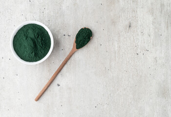 Fototapeta na wymiar Spirulina algae powder in a bowl and spoon over wooden table with copy space