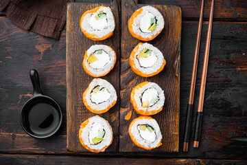 Philadelphia roll sushi with salmon, prawn, avocado, cream cheese, on old dark  wooden table background, top view flat lay