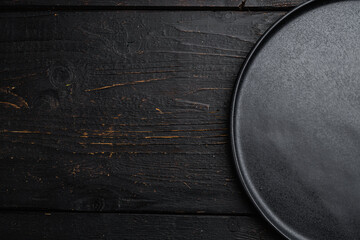 Top view of black plate, on black wooden table background