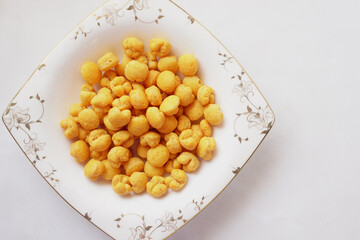 puffed corn rings chips in black bowl on white background
