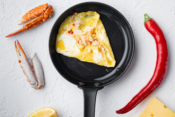 Thai  Asian omelette, fresh red chilli, brown and white crabmeat, lemon, Cheddar cheese, eggs, on frying iron pan, on white background, top view flat lay - obrazy, fototapety, plakaty