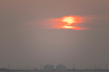  red sun in the sky and evening clouds are over Tangyard. In the petrochemical industry .The front is sea and white waves.