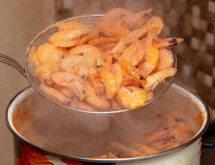 Red shrimps are boiled in a saucepan.