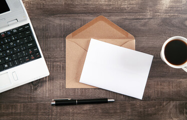 Mail envelope, coffee, pen and laptop on the desk.