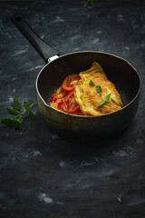 Breakfast omelet with tomatoes and rice on a dark background