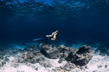 Woman freediver underwater in ocean. Freediving with fins in deep sea