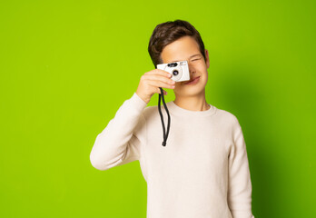Little boy with photo camera isolated over green background.