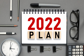 2022 plan. the inscription on the notebook. business concept. notepad on a gray background. glasses, pen, pencil, watch, calculator