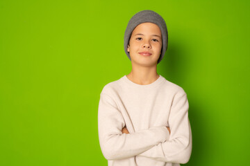 Photo of adorable young happy boy looking at camera with arms folded isolated over green background