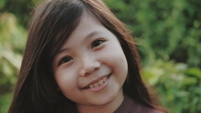 Close up Cute Little Asian girl in brown sweater smiles happily in winter. with Spece For Text.